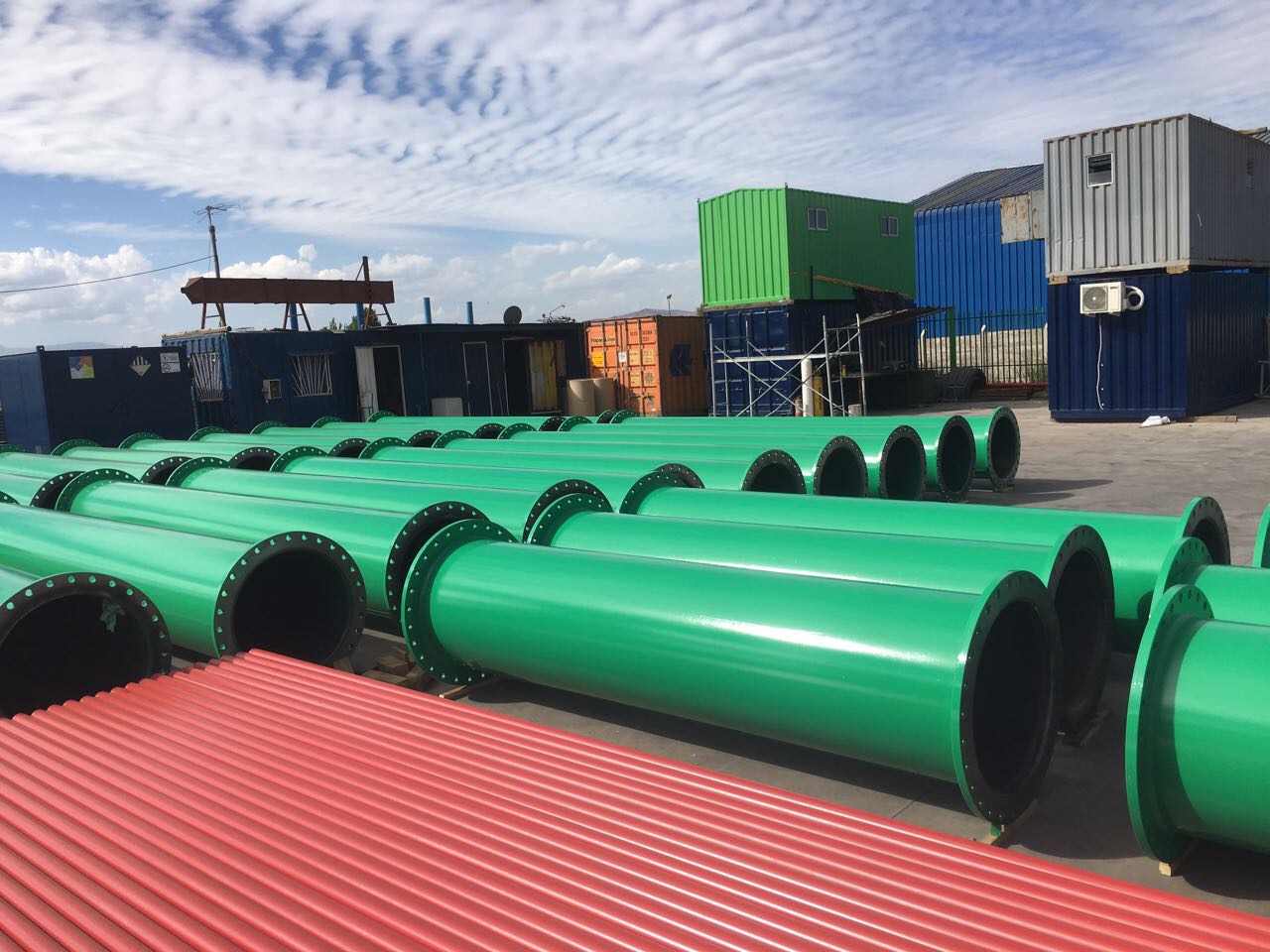 Lote completo de spools de gran diámetro pintados en verde alineados en patio industrial — Kronos Mining